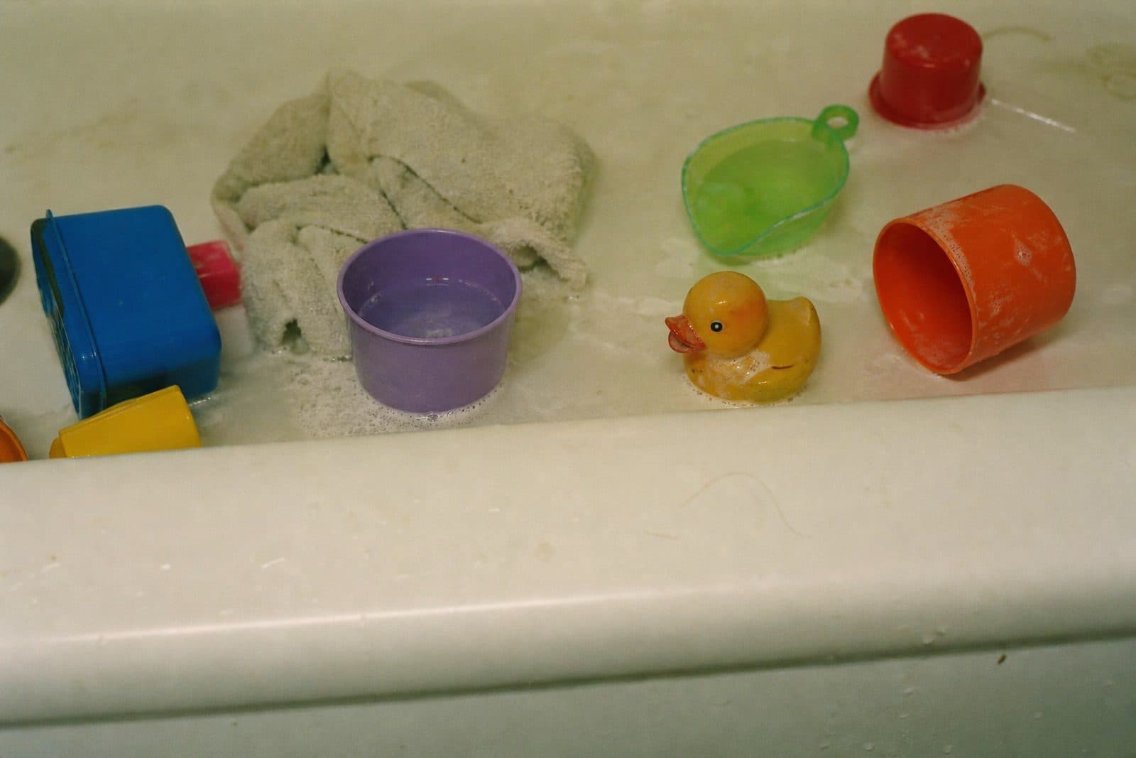 Stacking cups and a toy boat on the rim of a bathtub